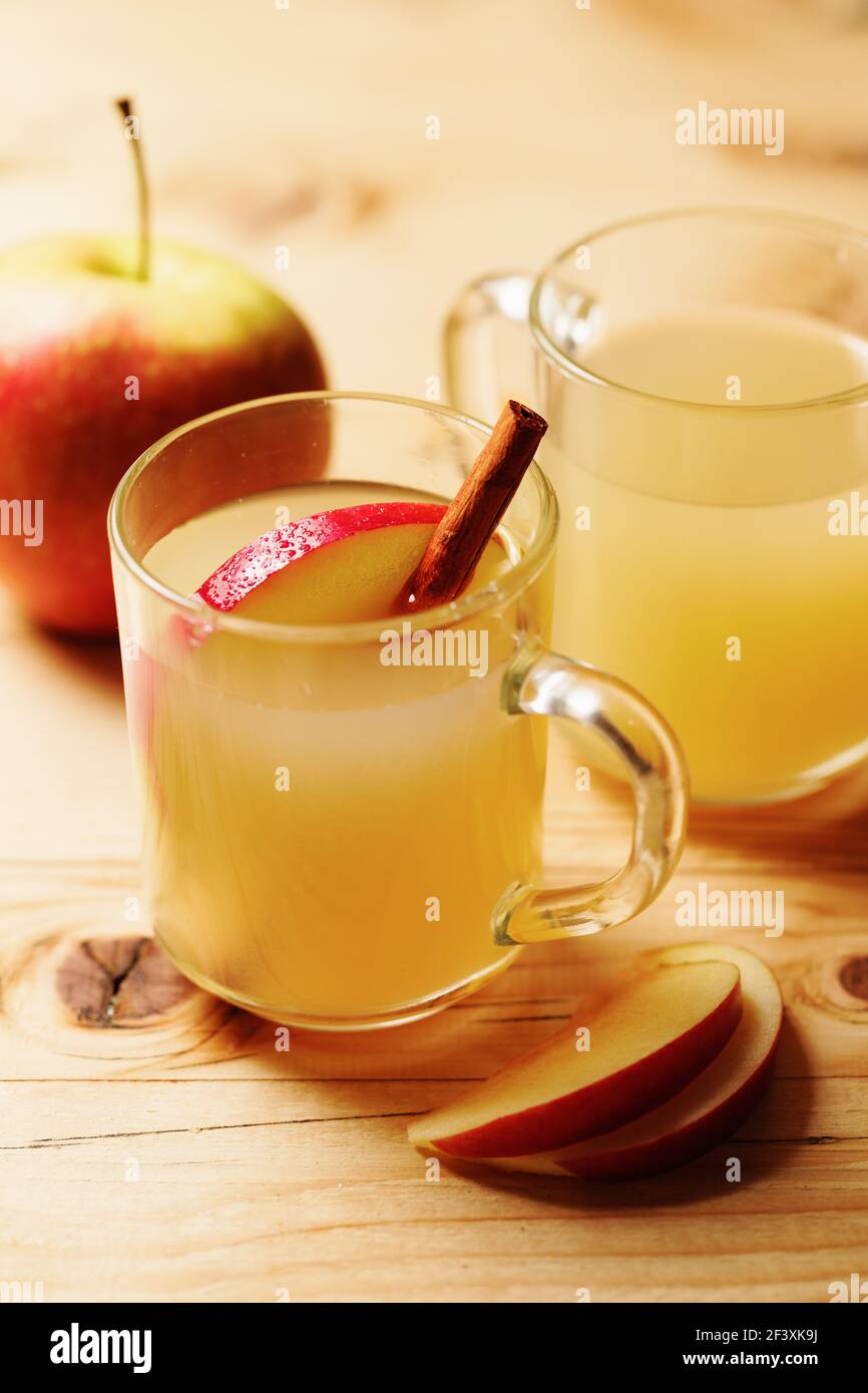 Sidra de manzana casera en una taza de vidrio con canela y.. una rebanada de manzana sobre una mesa de madera Foto de stock