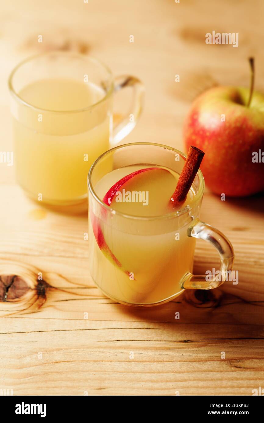 Sidra de manzana casera en una taza de vidrio con canela y.. una rebanada de manzana sobre una mesa de madera Foto de stock