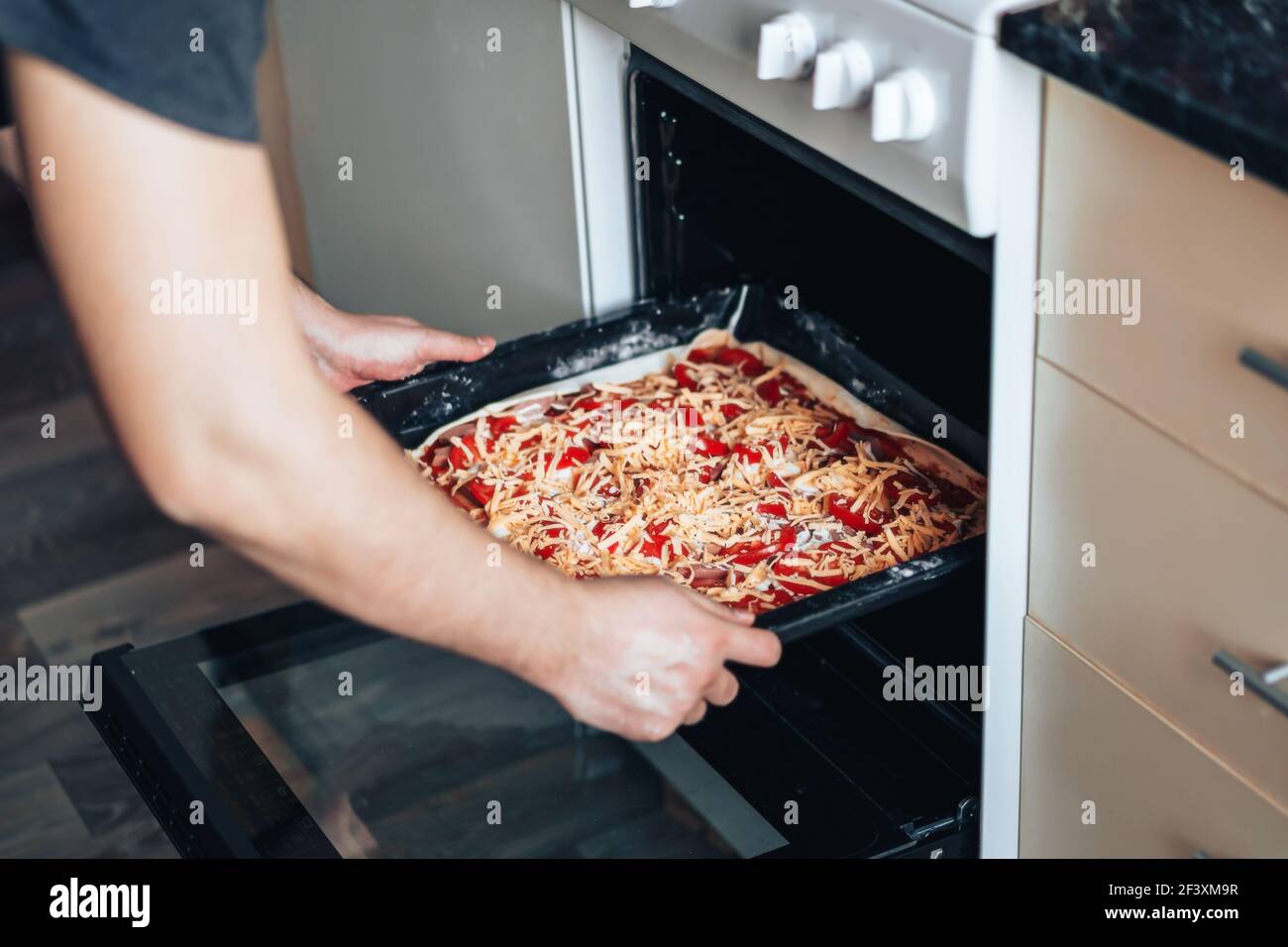 El hombre hace pizza en casa en la cocina. Coloca la hoja de hornear en el  horno para la pizza Fotografía de stock - Alamy