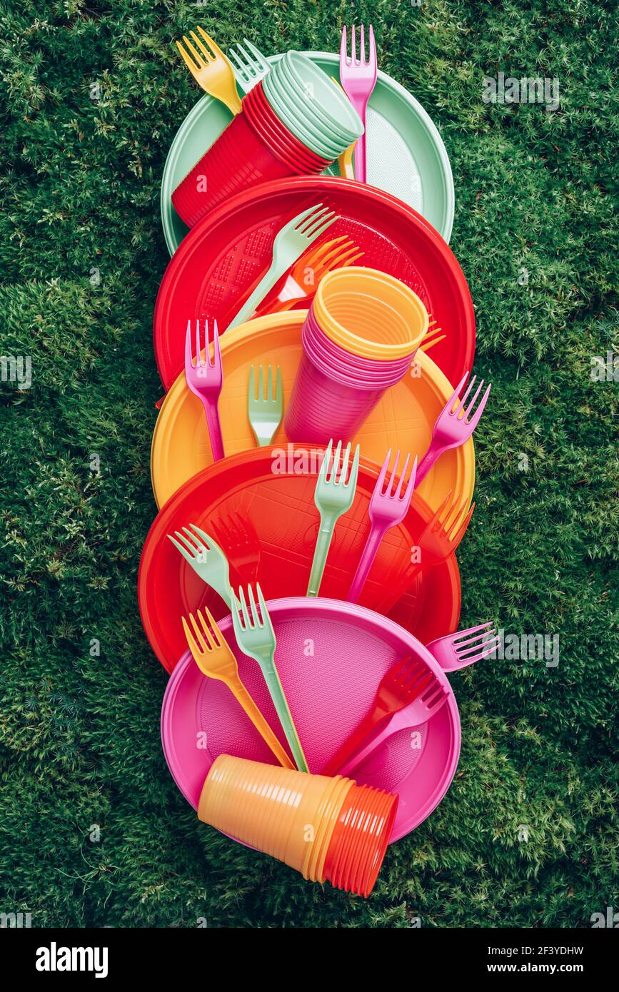 Vajilla desechable de plástico de color sobre fondo verde de musgo de  hierba. Vista superior. Espacio de copia. Cumpleaños picnic utensilio.  Reciclaje de plástico y ecología Fotografía de stock - Alamy