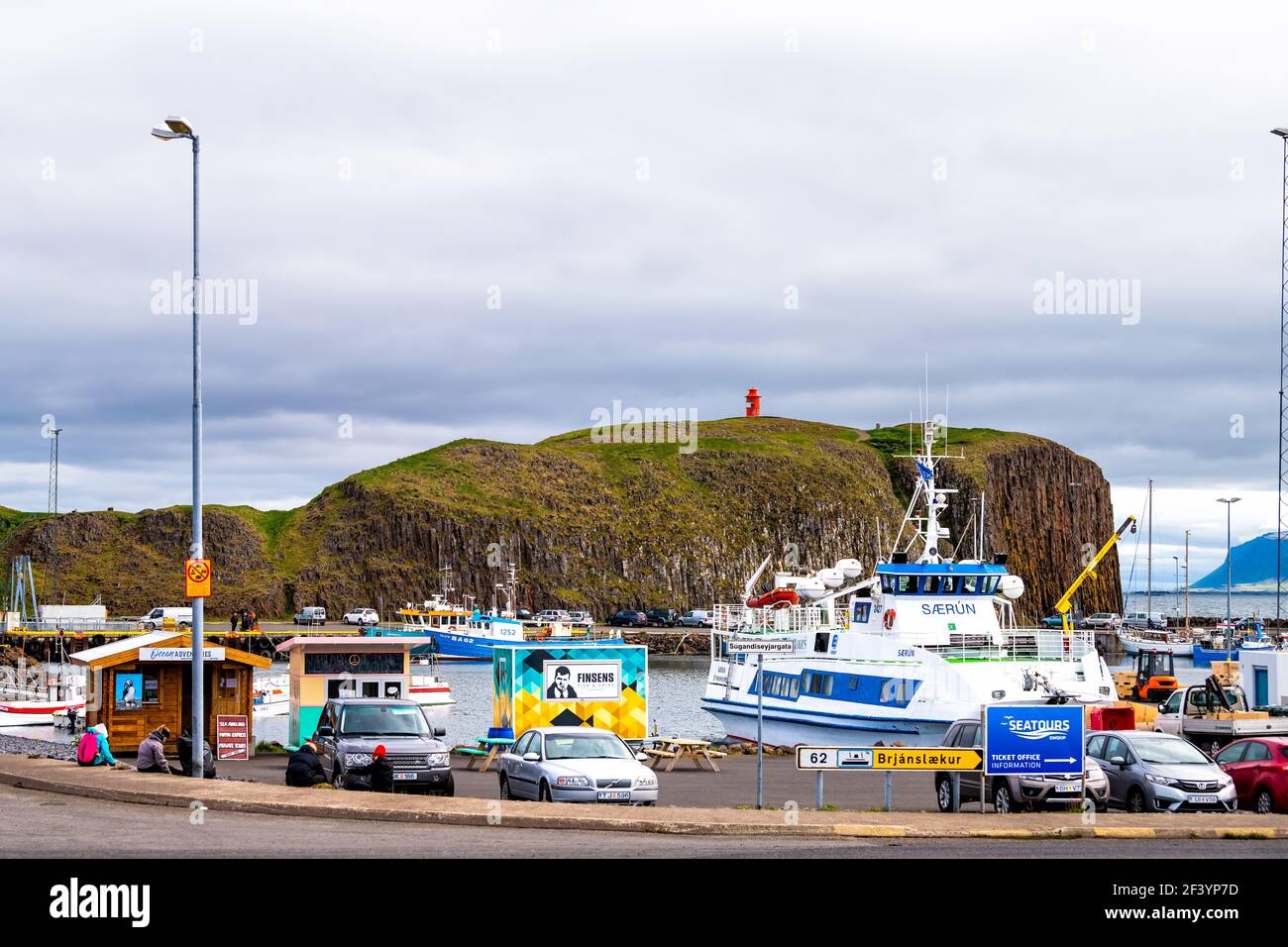 Stykkisholmur, Islandia - 18 de junio de 2018: Día nublado pequeño pueblo de pescadores en la península de Snaefellsnes con barcos tour barcos y estacionamiento Foto de stock