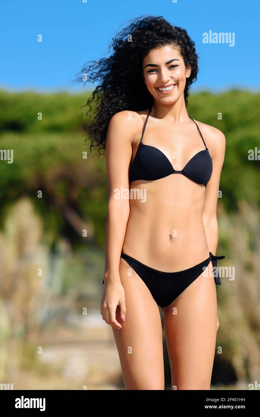 Joven mujer árabe con hermoso cuerpo en traje de baño sonriendo en un .  Joven mujer árabe con cuerpo hermoso en traje de baño sonriendo en una  playa tropical. Mujer morena con