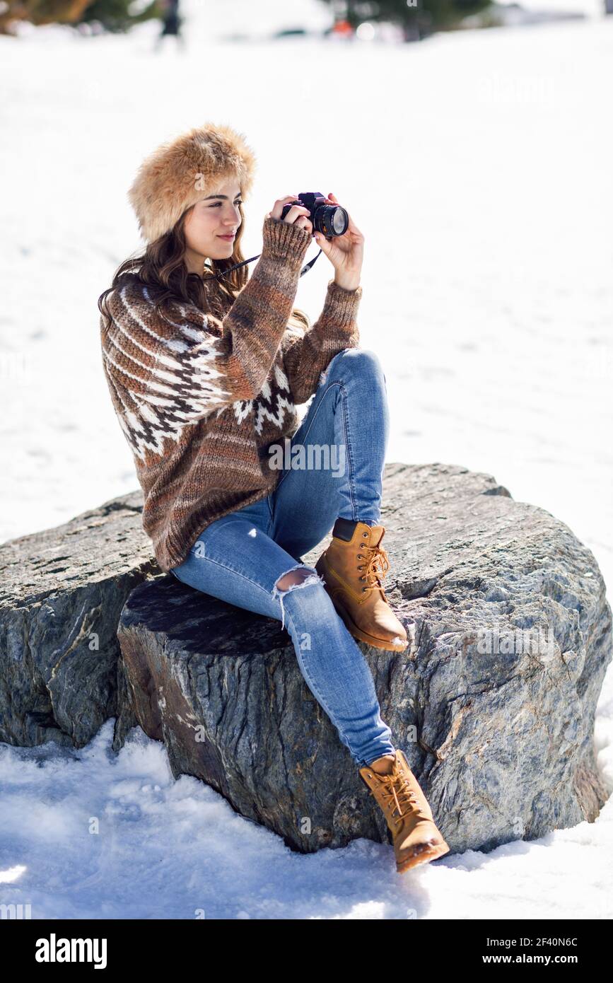 Mujer joven tomando fotografías en las montañas nevadas en invierno, en Sierra Nevada, Granada, España. Mujer invierno. Mujer joven tomando fotografías en las montañas nevadas Fotografía de stock -