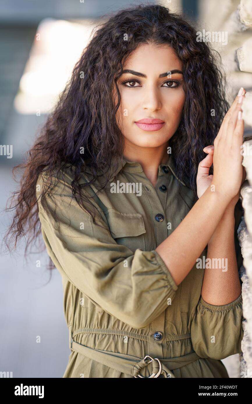 Joven Arab Mujer con pelo rizado en el fondo urbano. Joven mujer árabe con pelo rizado al aire libre Foto de stock