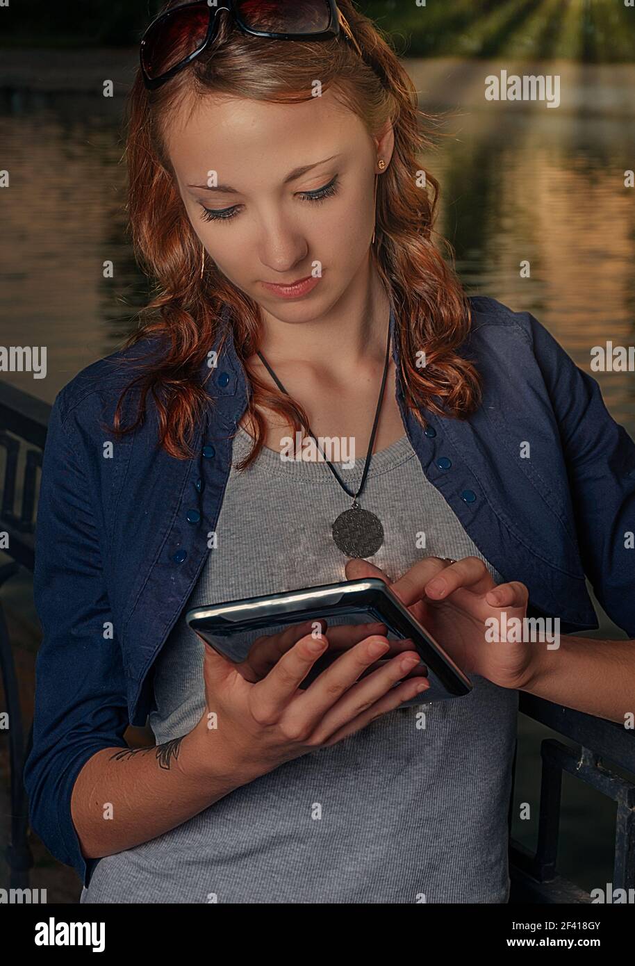 Mujer con e-lector posando al aire libre, la atención se concentró en gritar mirando hacia abajo. Mujer con lector electrónico posando al aire libre Foto de stock