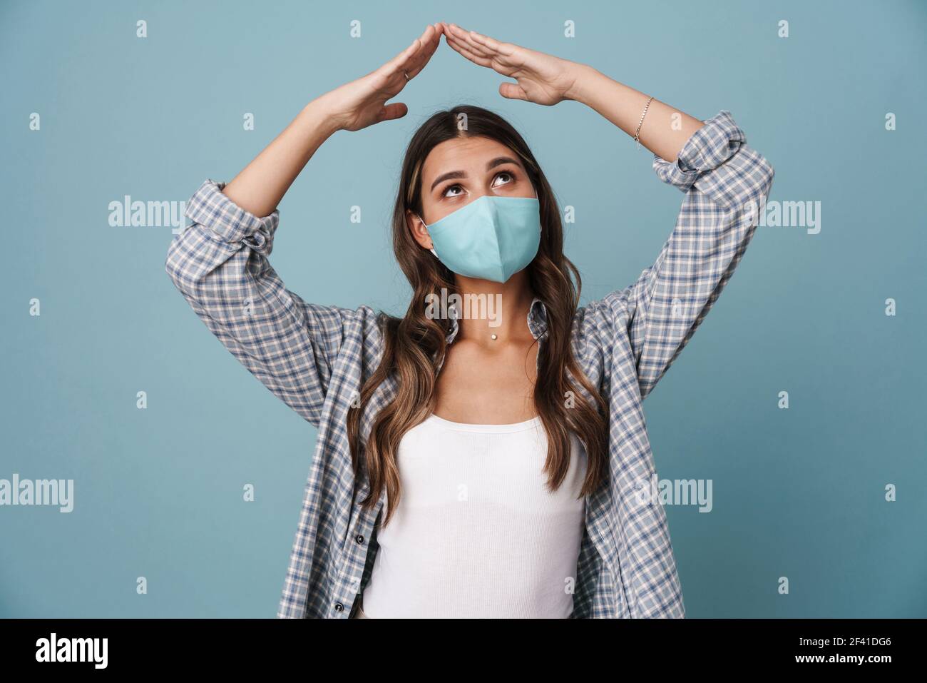 Chica encantadora en máscara protectora haciendo el gesto de la azotea  aislada sobre fondo azul Fotografía de stock - Alamy