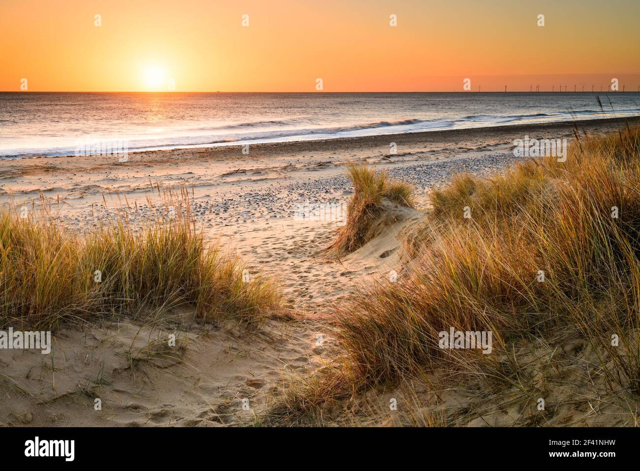 Un camino arenoso serpentea a través de las dunas de arena y.. Hacia el mar en la costa de Norfolk en Winterton on El mar como el sol de la mañana temprano se eleva por encima de t Foto de stock