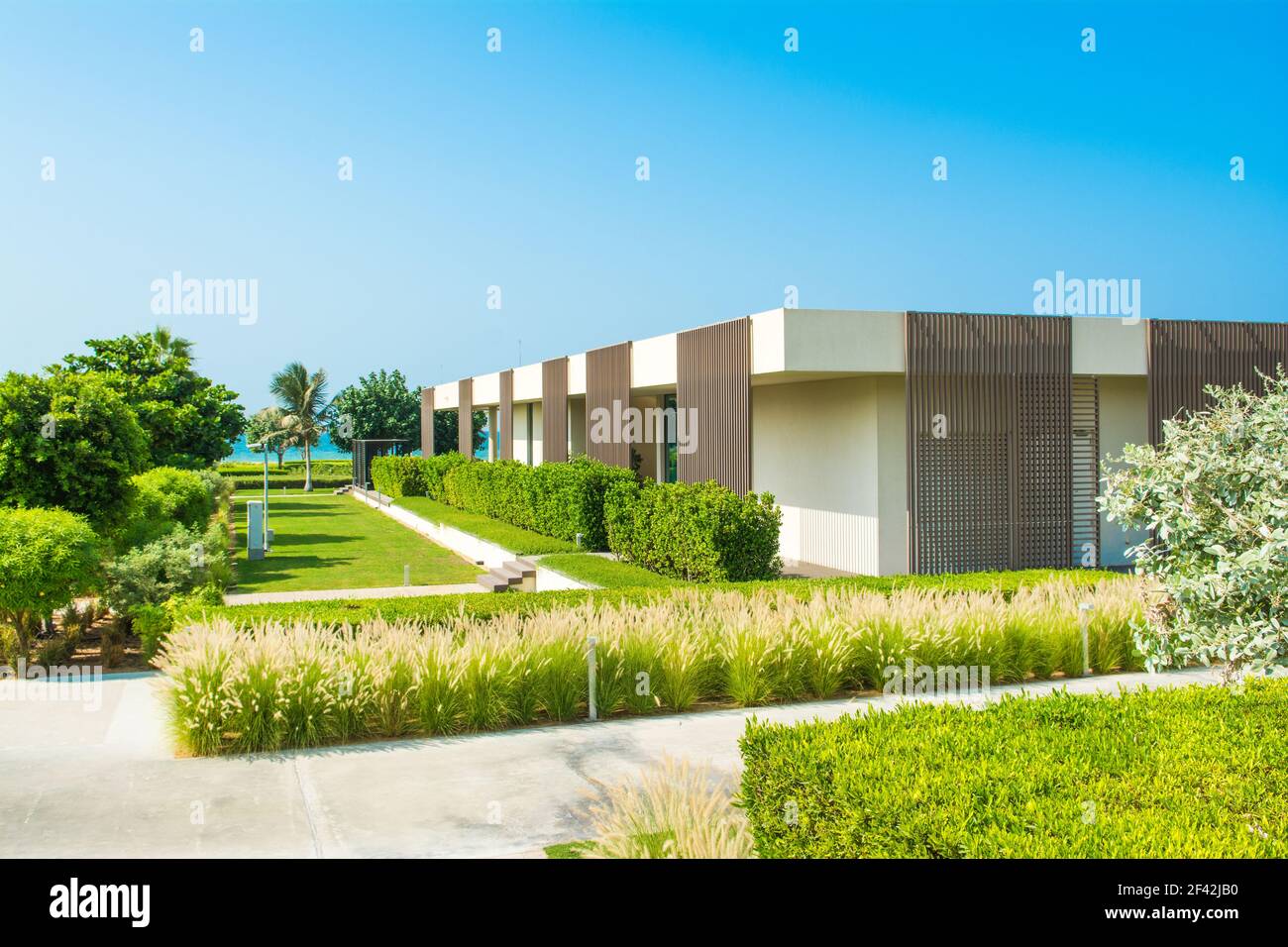 Ajman, Emiratos Árabes Unidos - 30 de octubre de 2018: Paisaje con villas de diseño moderno y jardín en un hotel de lujo en la costa de al Zorah Foto de stock
