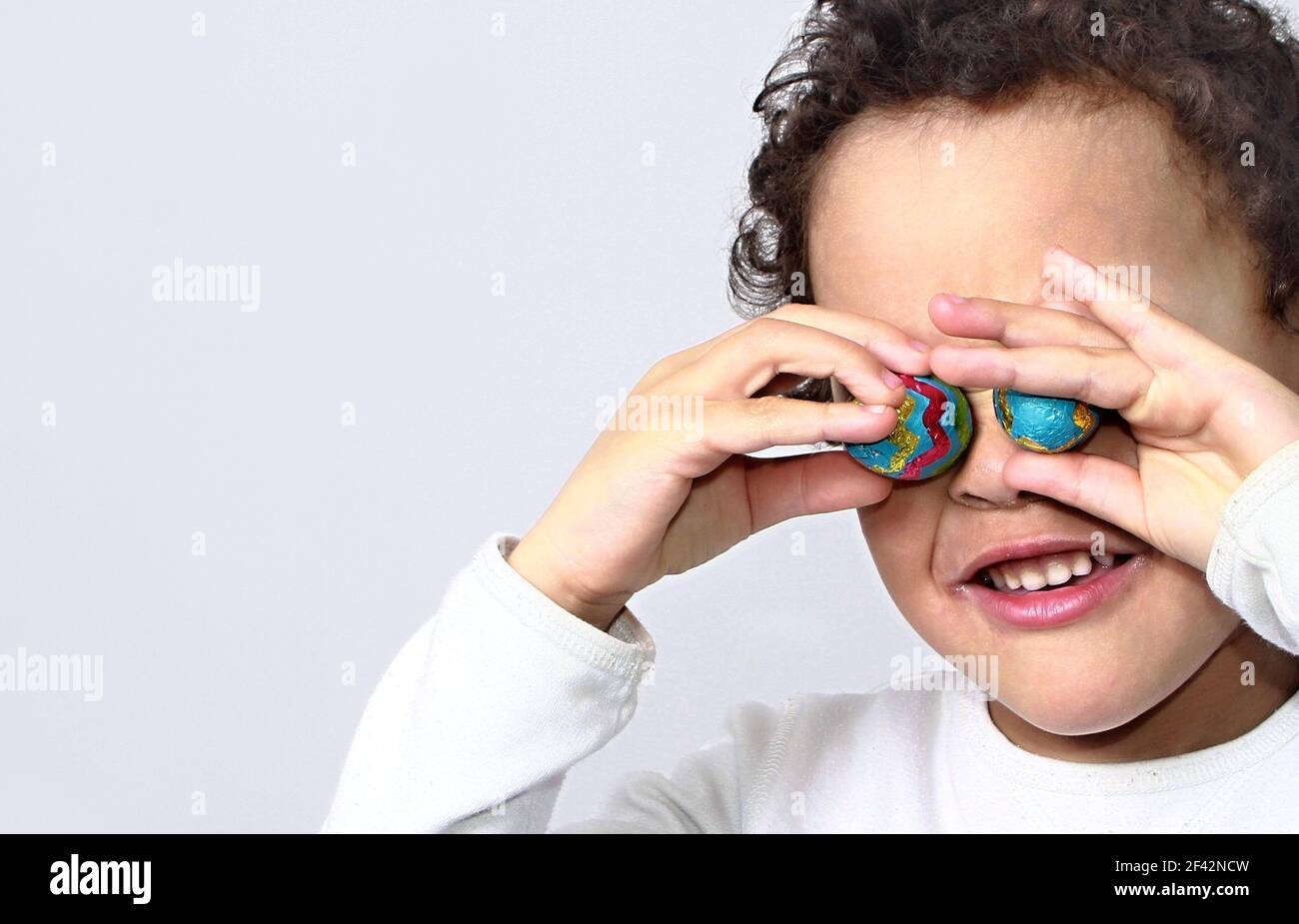 Niño con chocolate huevos de Pascua en muchos colores blanco fondo foto de stock Foto de stock