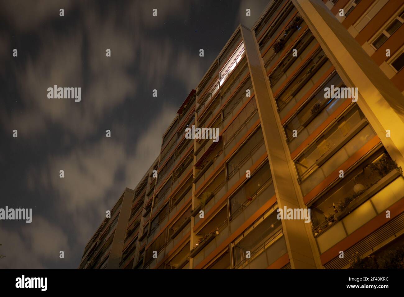 Fachada de un edificio residencial alto en la noche oscura. Foto de exposición larga con estrellas en el cielo y nubes borrosas. Foto de stock