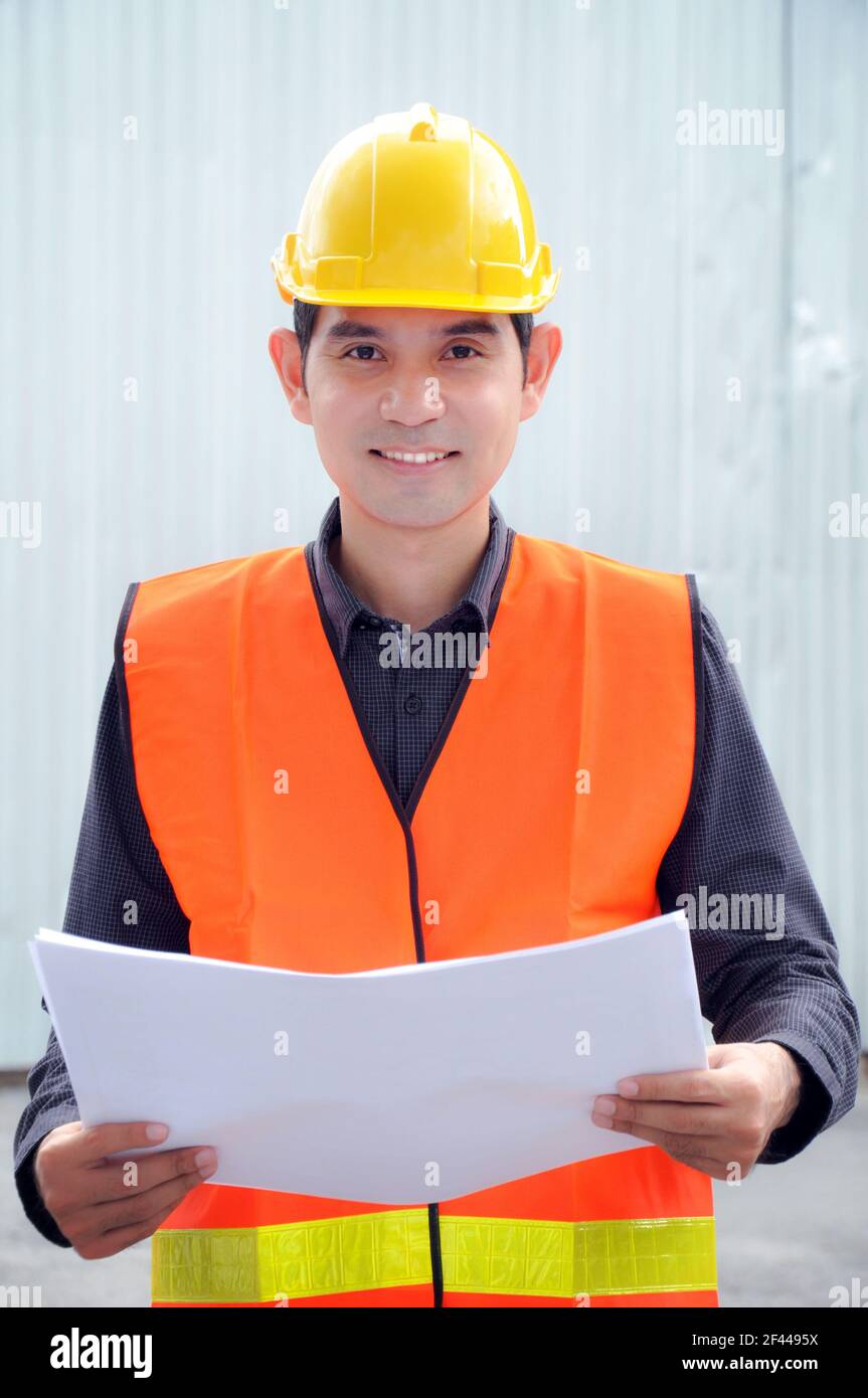 Ingeniero asiático o capataz con chaleco de seguridad y casco Foto de stock