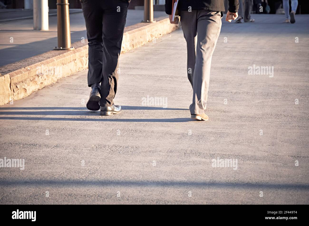 Piernas de dos hombres caminando sobre el pavimento Foto de stock