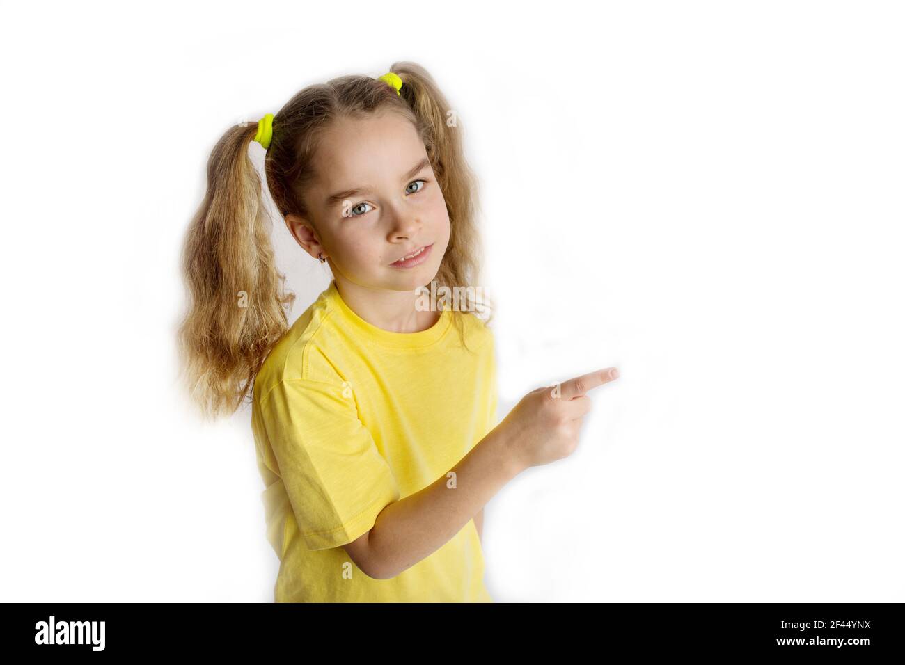 Una niña rubia en una camiseta amarilla hace gestos, aislada en un retrato  de estudio de niños de fondo blanco. Concepto de estilo de vida infantil  Fotografía de stock - Alamy