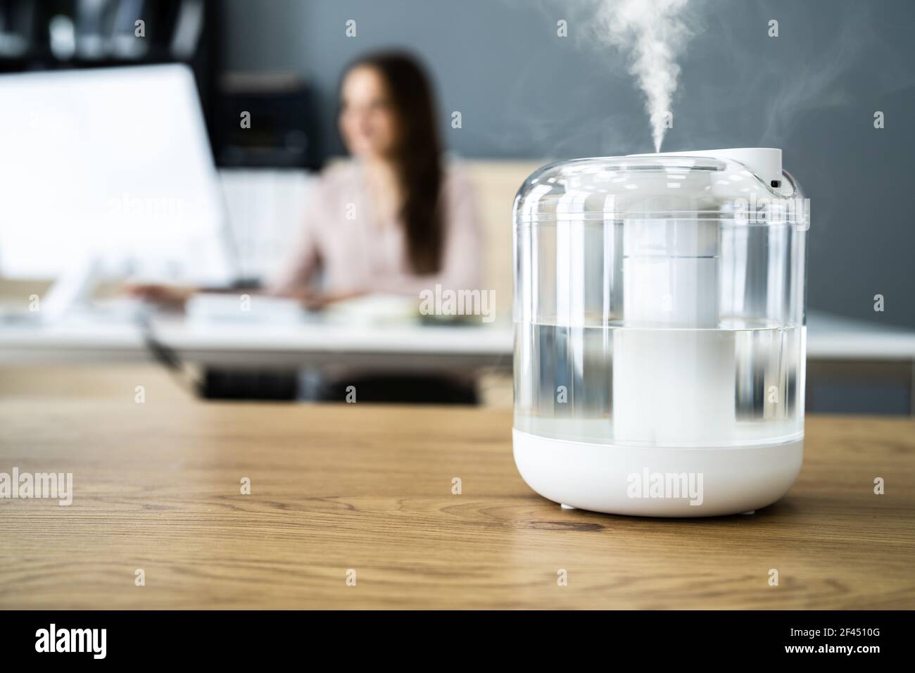 Dispositivo humidificador de aire en el escritorio de la oficina cerca de  la mujer que trabaja Fotografía de stock - Alamy