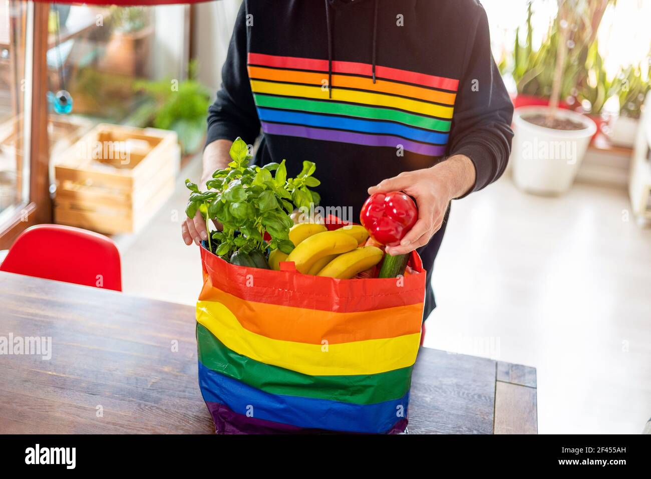 Hombre joven con sudadera arcoiris desempacando bolsa de comida en inicio  Fotografía de stock - Alamy