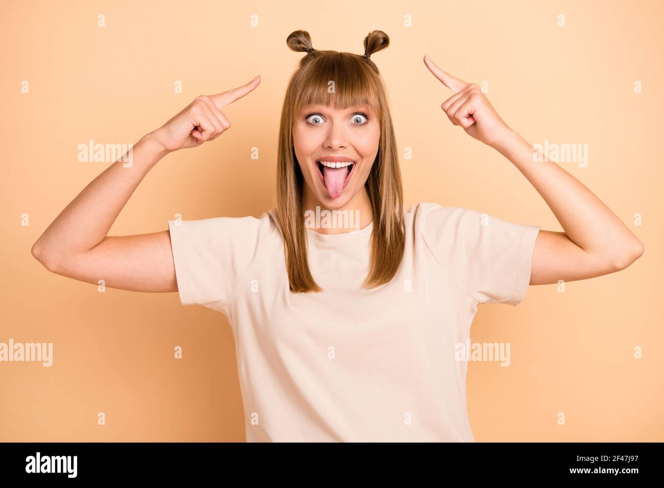 Foto retrato de modelo divertido que muestra la lengua mugrimacing señalando  el pelo mirando tonto aislado sobre fondo color beige pastel Fotografía de  stock - Alamy