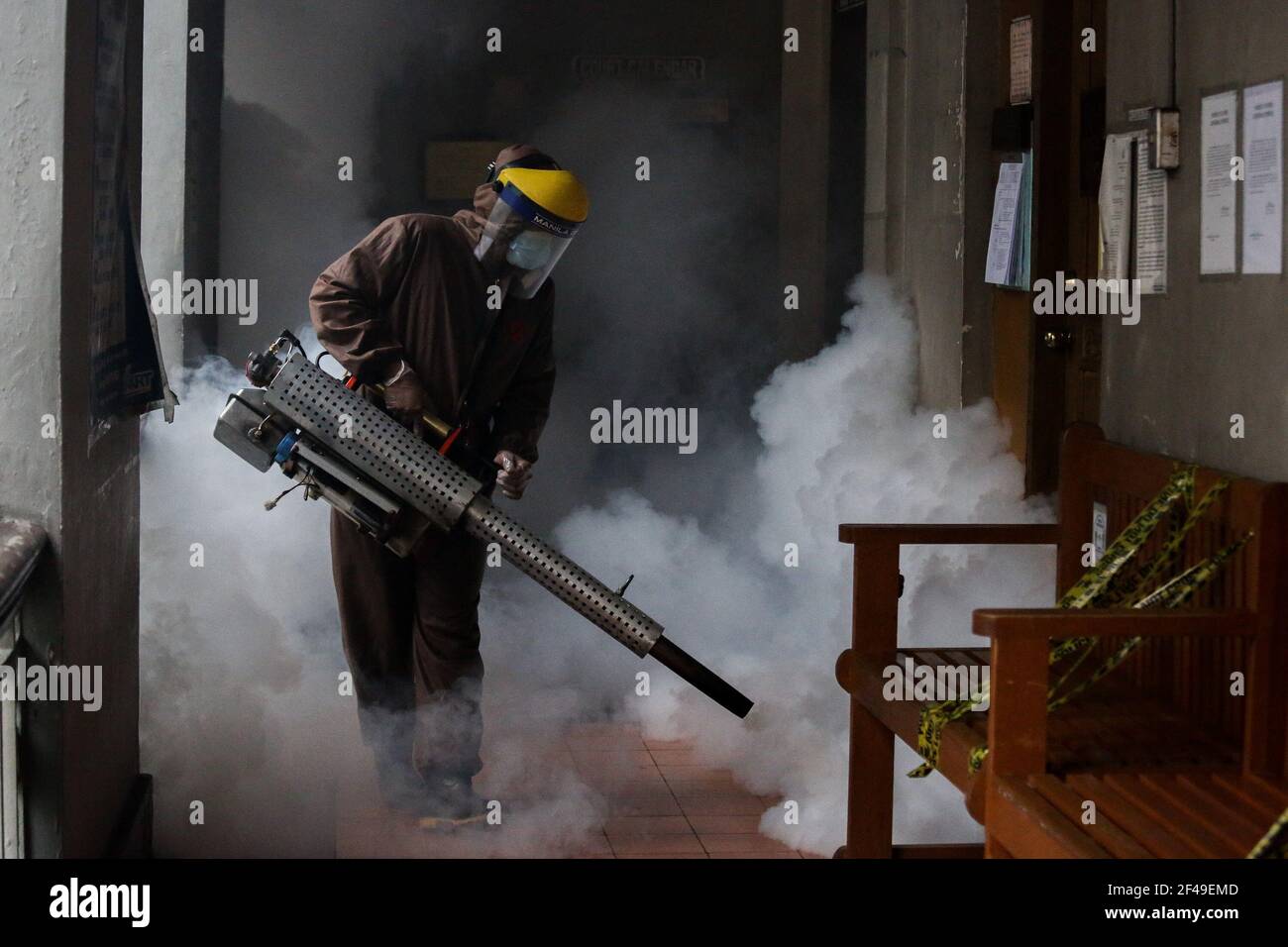 Un trabajador desinfecta un pasillo como medida de precaución contra la propagación del COVID-19 dentro de un edificio del gobierno en Manila casi un año después de que la ciudad fuera puesta bajo cuarentena comunitaria. Filipinas. Foto de stock