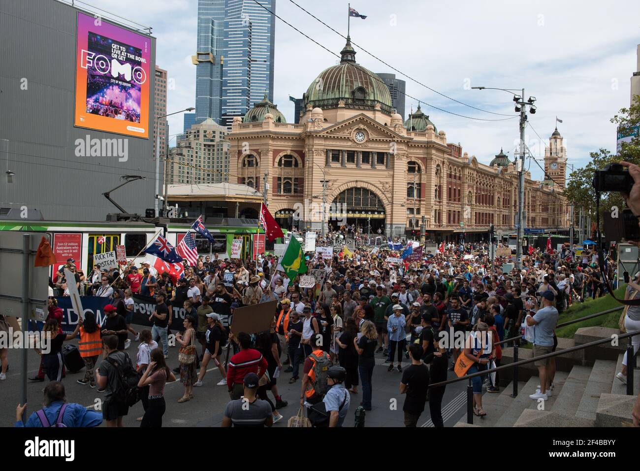 Melbourne, Australia 20 de marzo de 2021, los manifestantes pasan por la estación de Flinders Stree mientras salen a las calles en el Freedom Rally que fue parte de una demostración del planeado "World Wide Rally for Freedom" que fue organizado para llamar a la libertad de elección, el discurso y el movimiento. Crédito: Michael Currie/Alamy Live News Foto de stock