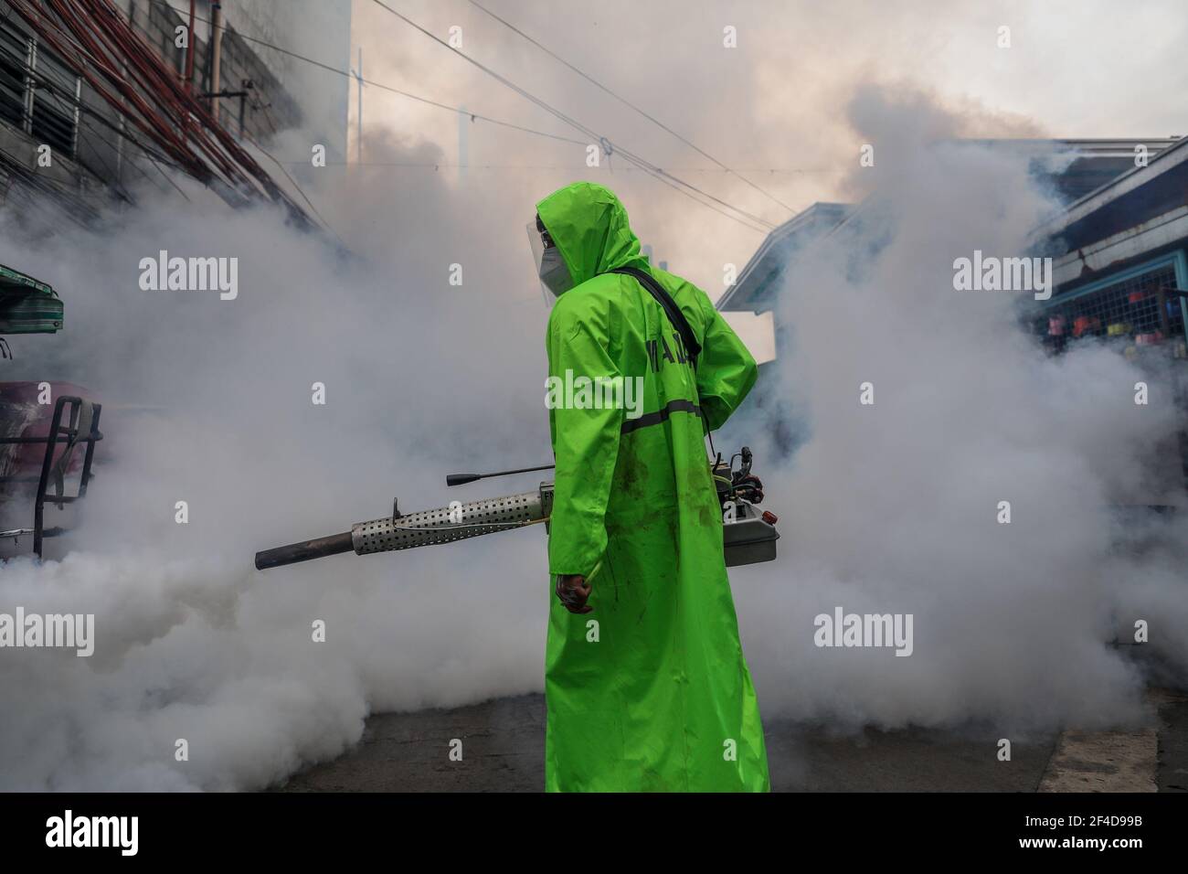 Un trabajador de saneamiento fumiga dentro de una zona residencial cuando la capital filipina Marca un año bajo una cuarentena comunitaria para ayudar a combatir la propagación del coronavirus. Filipinas. Foto de stock