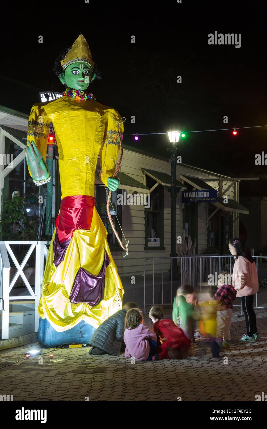 Una estatua del dios hindú Rama, iluminada por la noche. La gente está poniendo velas a sus pies para celebrar Diwali, el festival hindú de luces Foto de stock