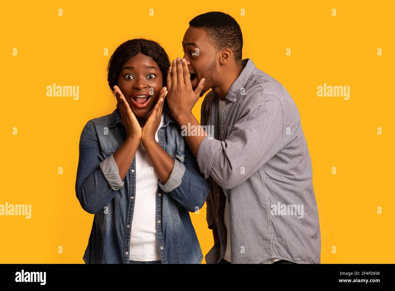 Compartiendo secreto. Black Guy chismeando con su emocionada novia Foto de stock
