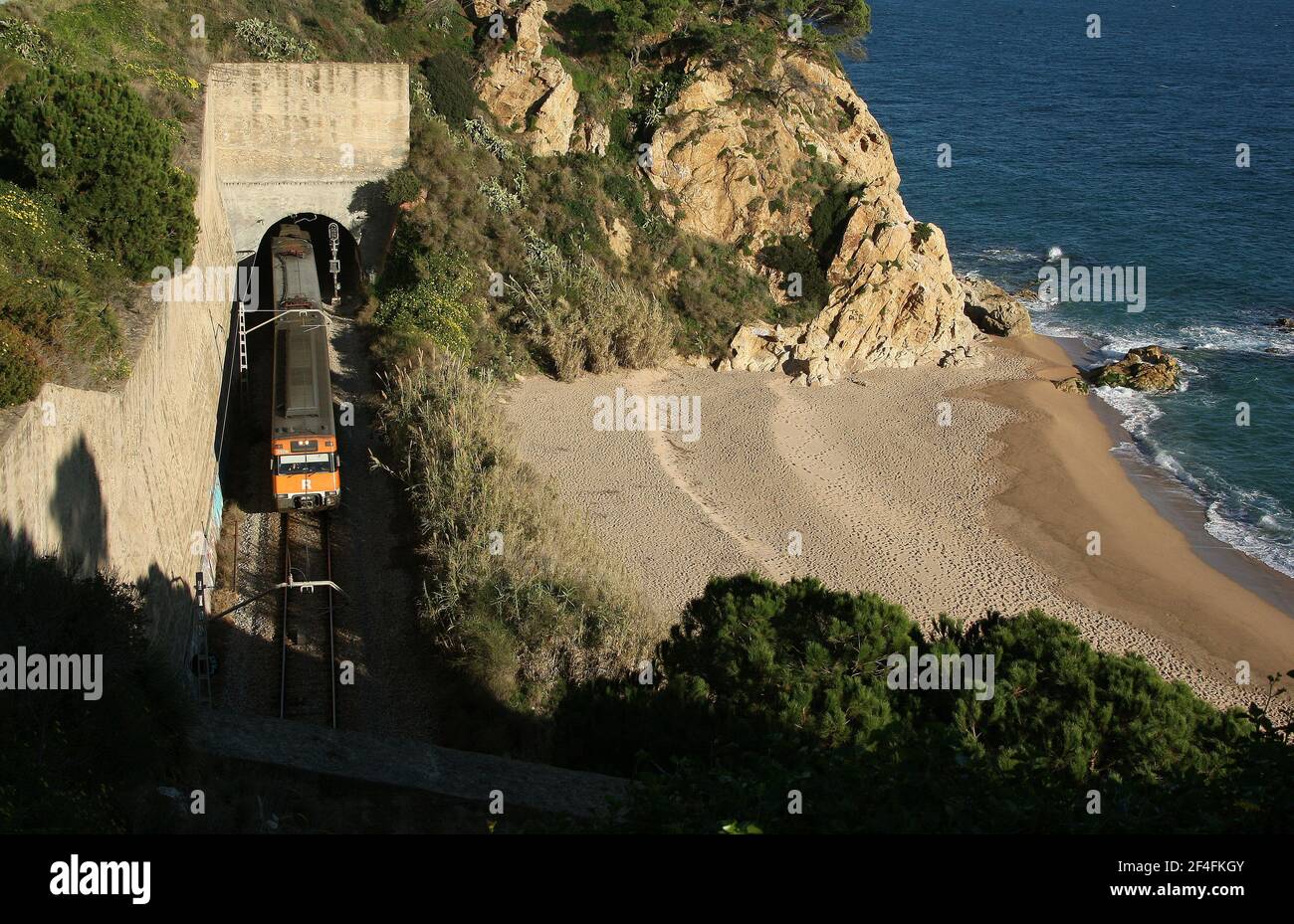 Tren Renfe saliendo de un túnel en la ciudad costera de Calella en la Costa Brava cerca de Barcelona en Cataluña España UE 2019 Foto de stock