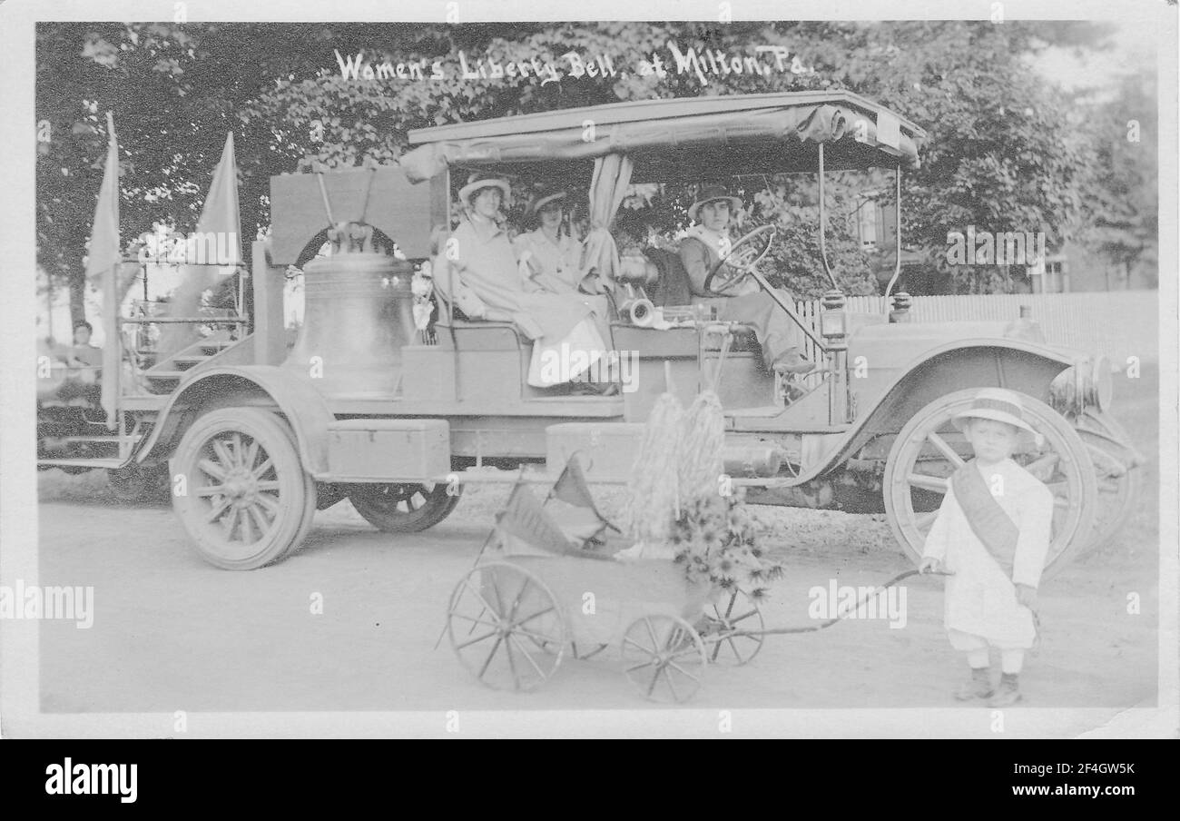 Un niño con un cochecito festoneado se encuentra frente a un camión que lleva la Campana de la Justicia, una réplica de la Campana de la Libertad fundida por los sufragios de Pensilvania y utilizada para hacer campaña entre 1915 y 1920, Milton, Pennsylvania, 1915. () Foto de stock