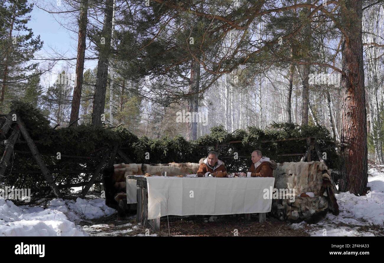 Tuva, Rusia. 21st de marzo de 2021. El presidente ruso Vladimir Putin toma un almuerzo con el ministro de Defensa Sergei Shoigu, a la izquierda, durante un viaje de fin de semana al bosque de taiga siberiano ruso el 21 de marzo de 2021 en Tuva, Rusia. Crédito: Planetpix/Alamy Live News Foto de stock