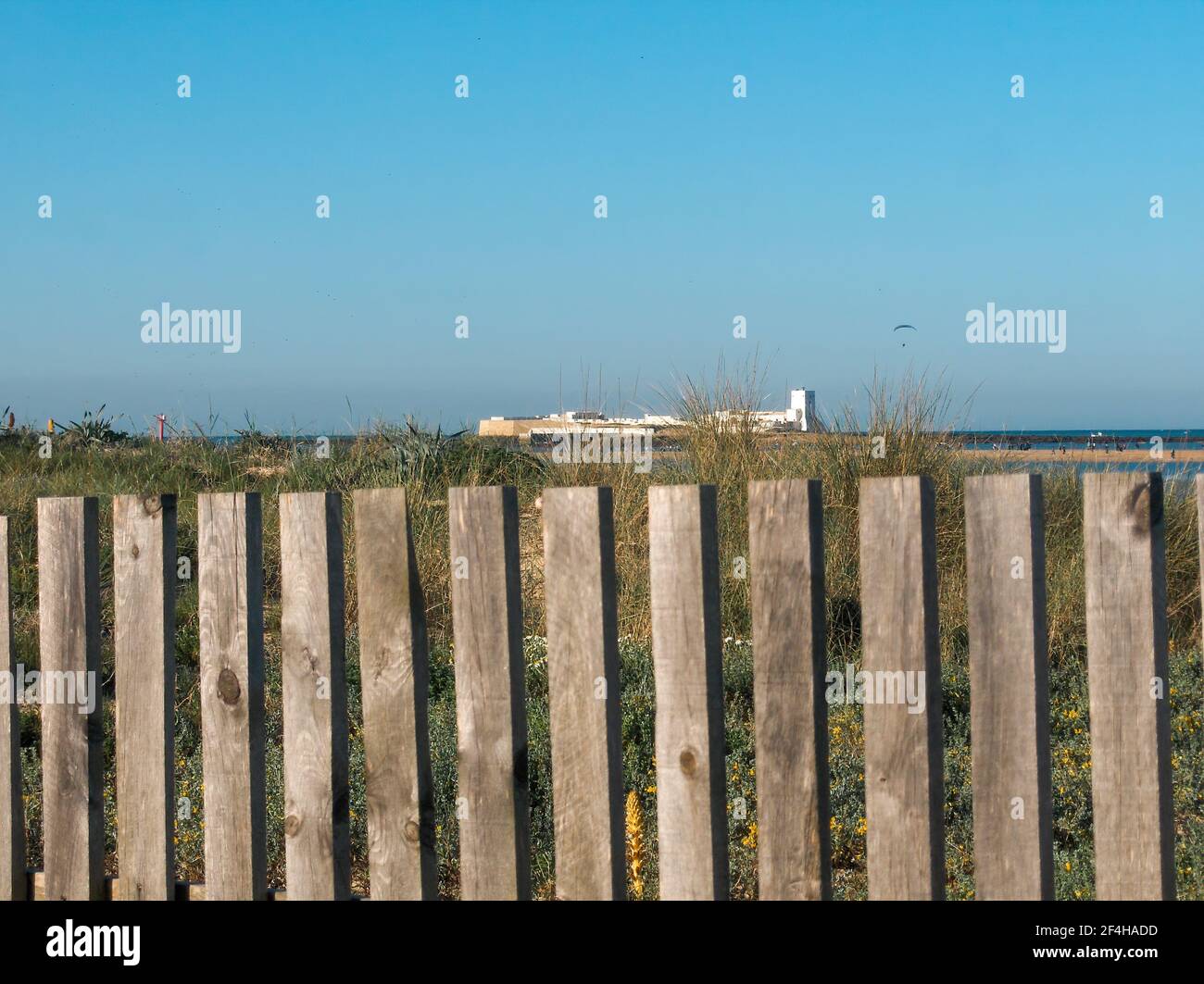 Vista distante del castillo de Sancti Petri detrás de las vallas de madera  de la playa en Chiclana de la Frontera, en la costa de Cádiz, Andalucía,  España Fotografía de stock -