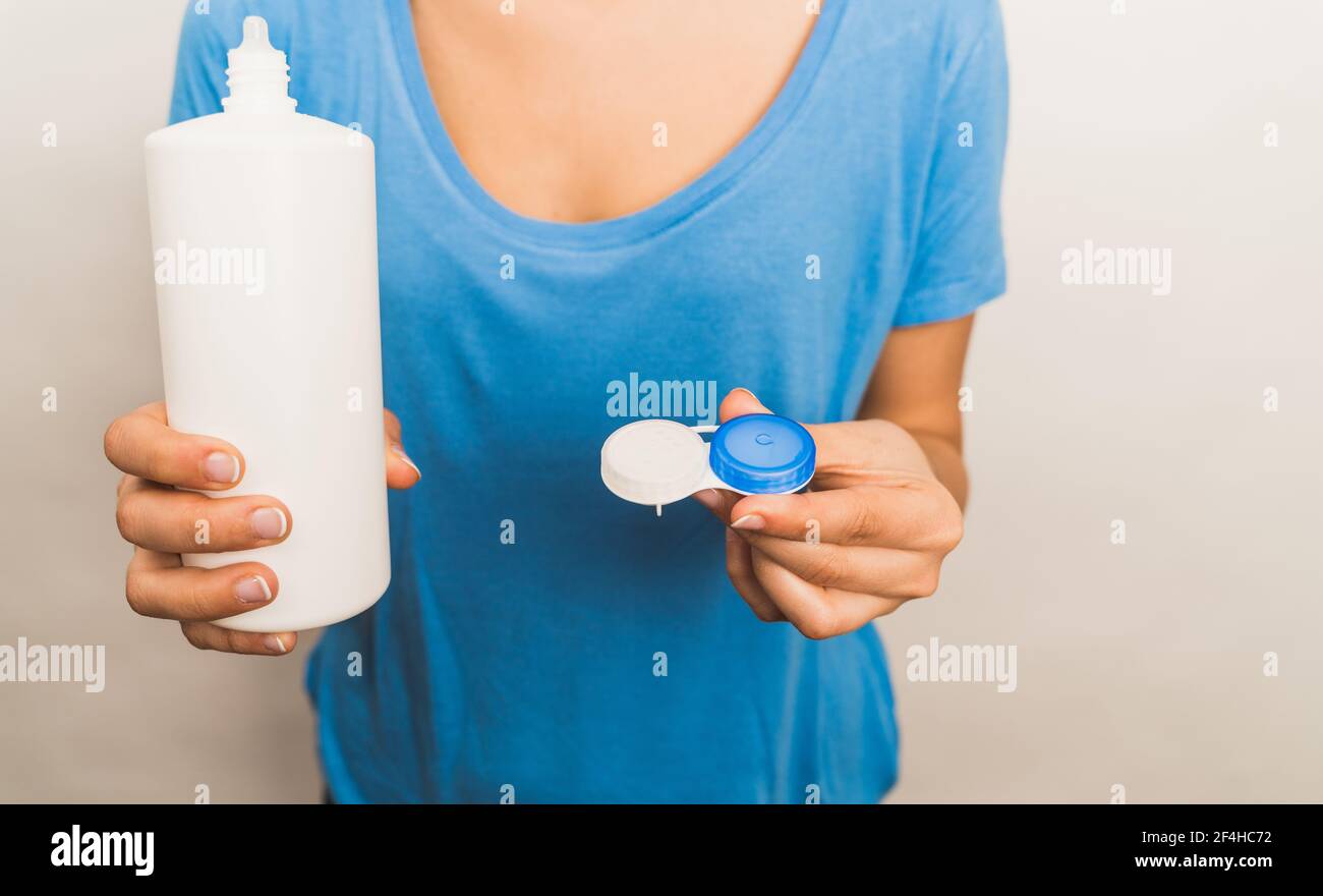 Cosecha mujer anónima vestir camisa azul casual mostrando plástico reutilizable paquete con lentes de contacto actuales y botella con solución Foto de stock