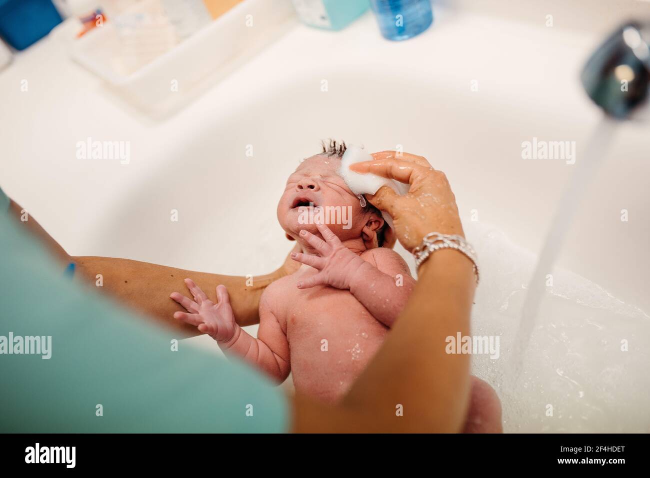 Alto ángulo de cosecha anónima enfermera con algodón dar esponja baño para un pequeño recién nacido en el hospital Fotografía de stock Alamy
