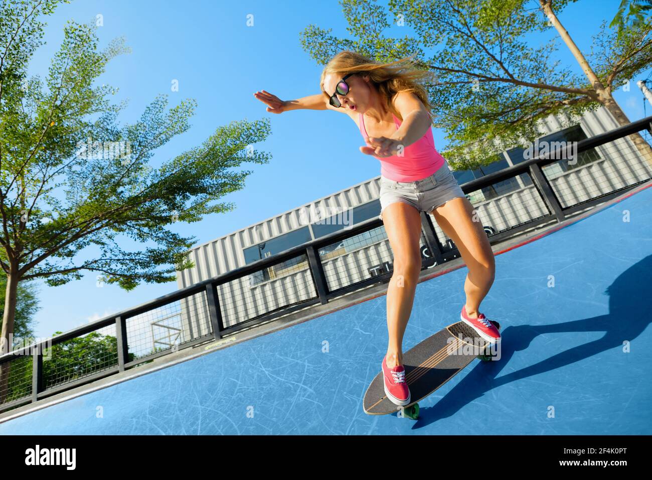 Patinador en acción. Mujer joven haciendo truco en surf skate longboard en  el exterior skatpark bowl. Clases de surf y skateboard en verano Fotografía  de stock - Alamy