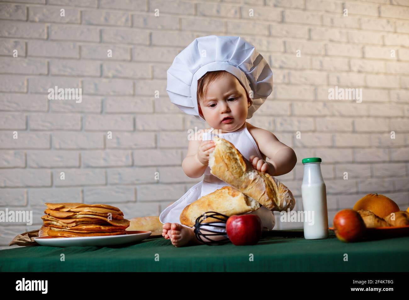 Niño vestido como cocinero en la cocina. Niño guapo vestido con un delantal  comiendo pan Fotografía de stock - Alamy