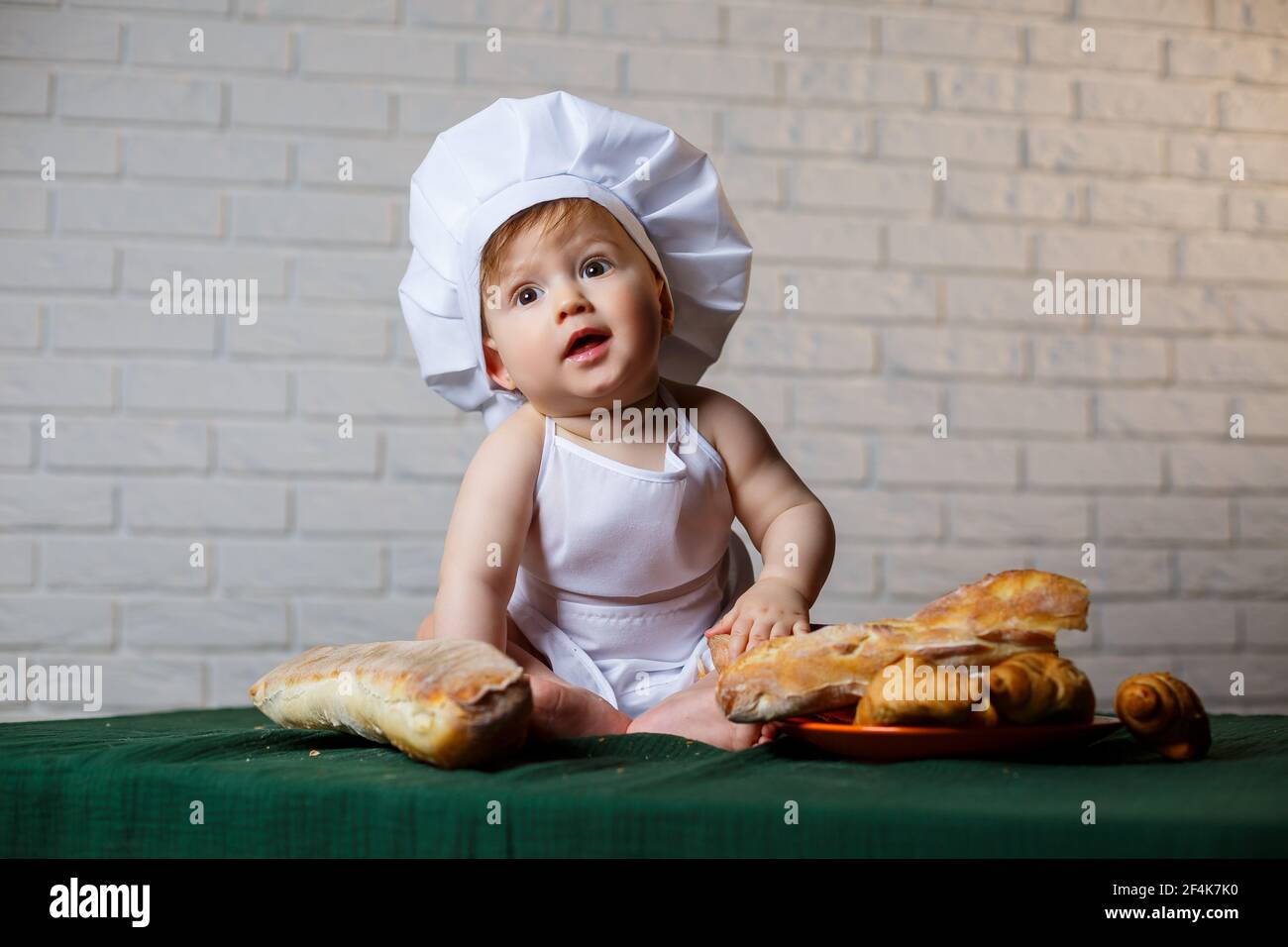 Niño pequeño en una gorra y con pan. Niño pequeño vestido como cocinero la cocina Fotografía - Alamy