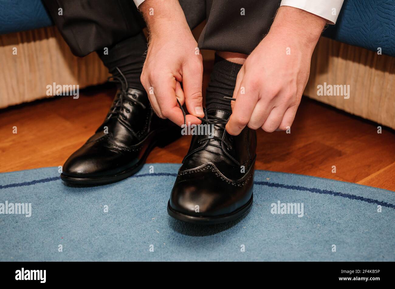 El tipo está atando los cordones en zapatos clásicos negros. El novio lleva  zapatos bonitos y ata sus cordones Fotografía de stock - Alamy