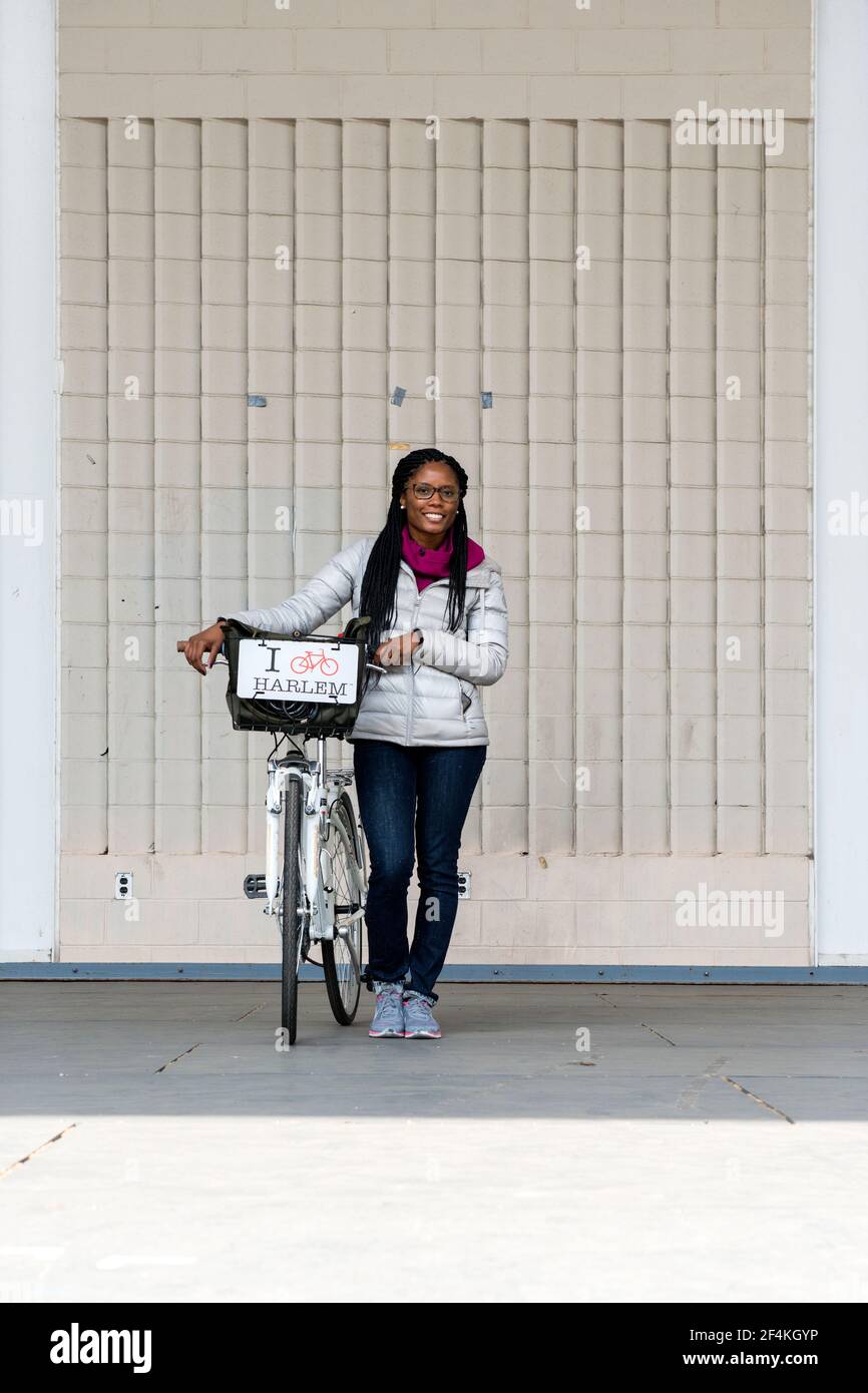 La Ciudad de Nueva York, EE.UU.. Atractiva afroamericana dando una visita guiada en bicicleta a través de Harlem, en Manhattan. Foto de stock