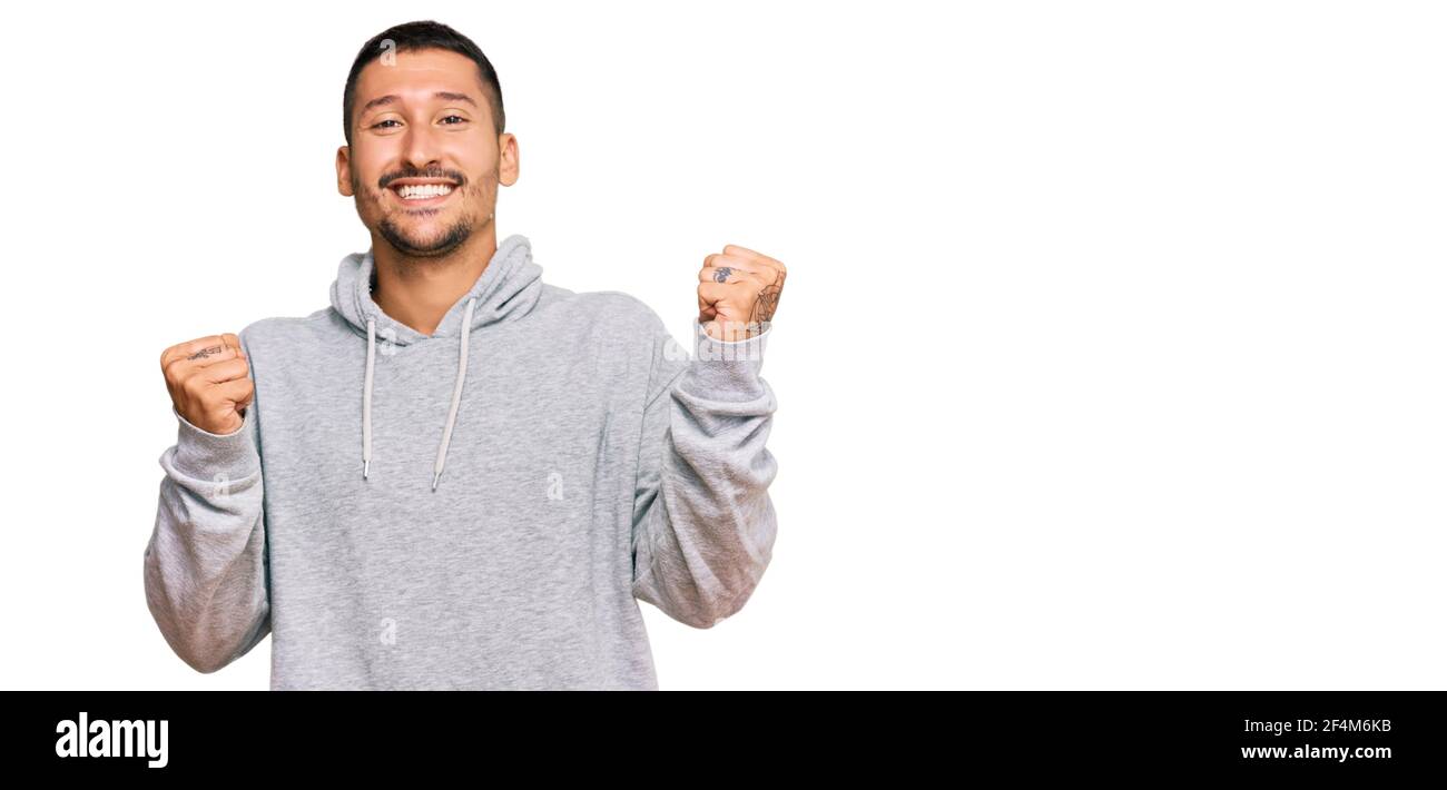 Hombre guapo con tatuajes con sudadera casual gritando orgulloso,  celebrando la victoria y el éxito muy emocionado con los brazos levantados  Fotografía de stock - Alamy