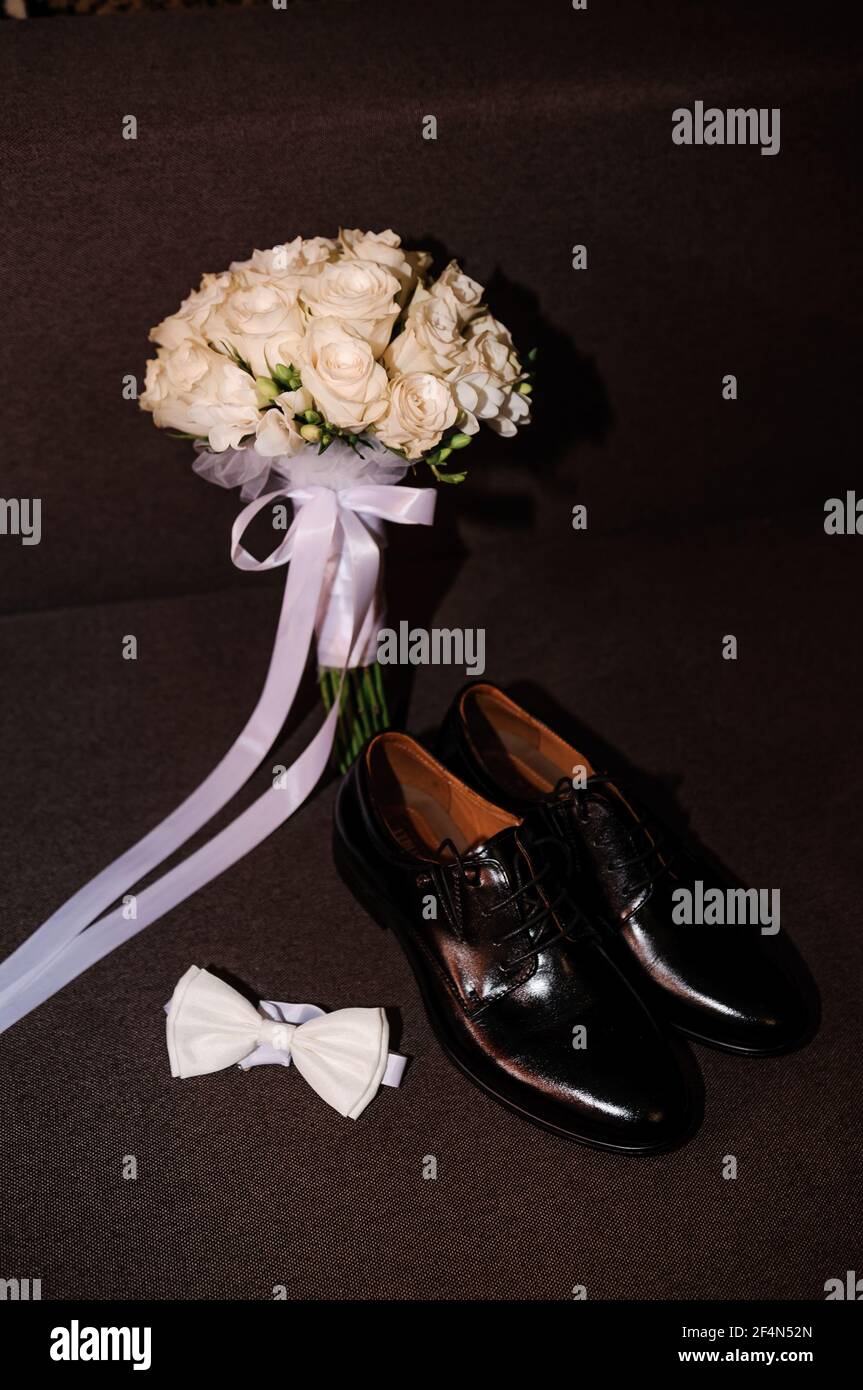Lazo blanco, zapatos negros clásicos y ramo de novia con rosas blancas  sobre fondo marrón Fotografía de stock - Alamy