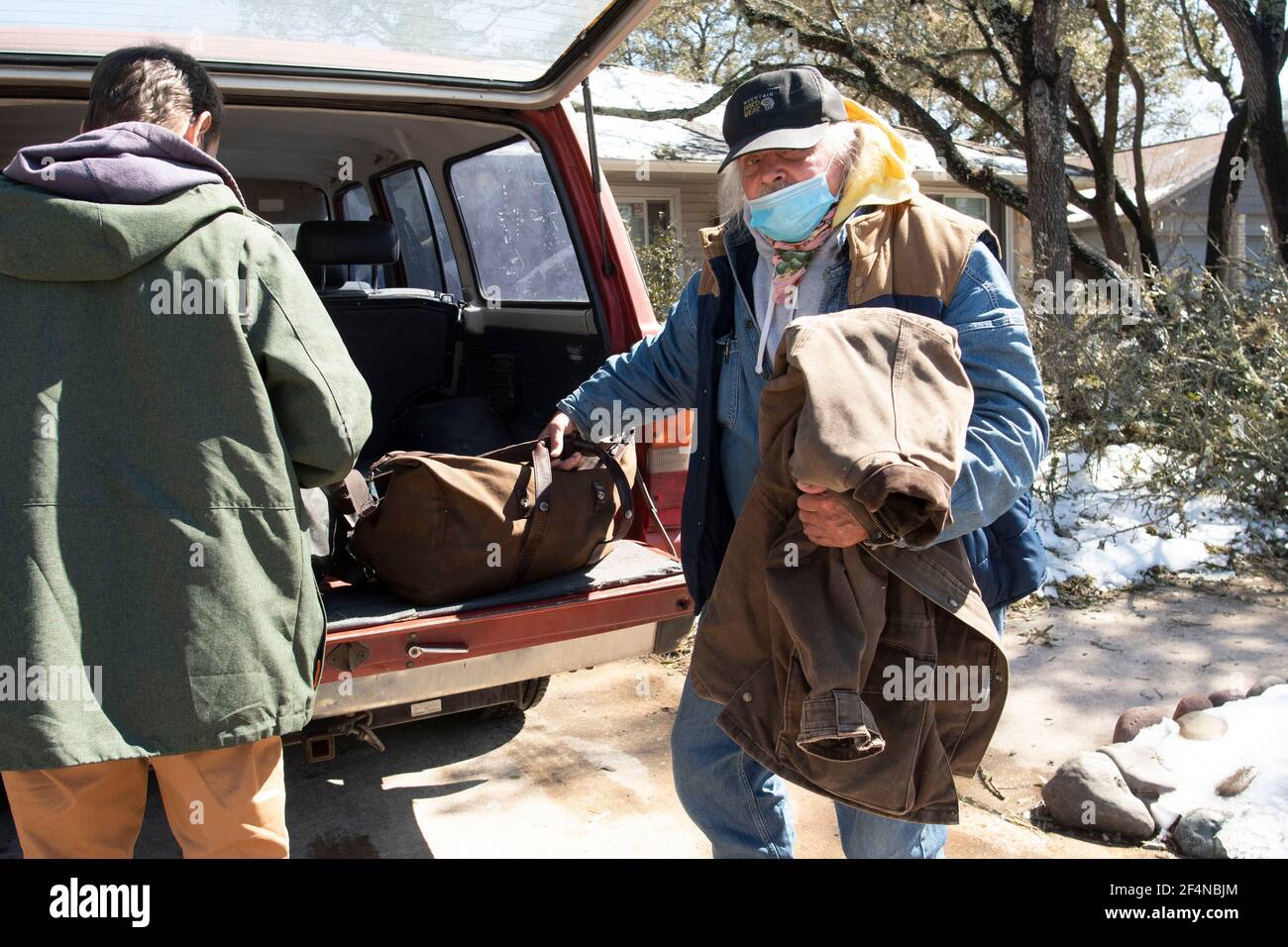 Austin, TX EE.UU. Feb 20, 2021: Veteranos sin hogar llegan para su primera noche a una casa sobria de gestión privada después de pasar una semana en un refugio cálido dirigido por la iglesia durante el reciente y severo clima invernal de Austin. Los miembros de la Iglesia organizaron el nuevo alojamiento después de que ambos hombres solicitaban ayuda para su alcoholismo. Foto de stock