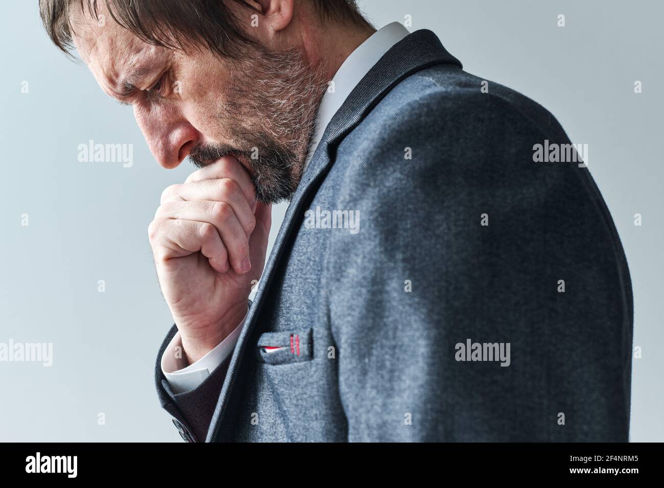 Cansado hombre de negocios pensivo sobrecargado de pensamientos contemplando con la mano en la barbilla, enfoque selectivo retrato Foto de stock