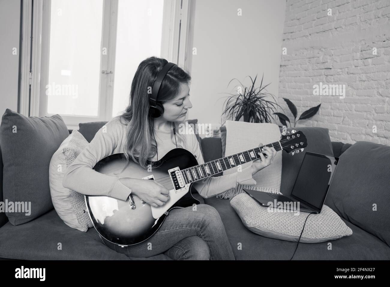 Mujer tocando guitarra eléctrica con portátil en la lección de música en  línea. Mujer divertirse viendo video tutorial sobre el aprendizaje de  canciones de rock. Pasatiempos y ocio Fotografía de stock -