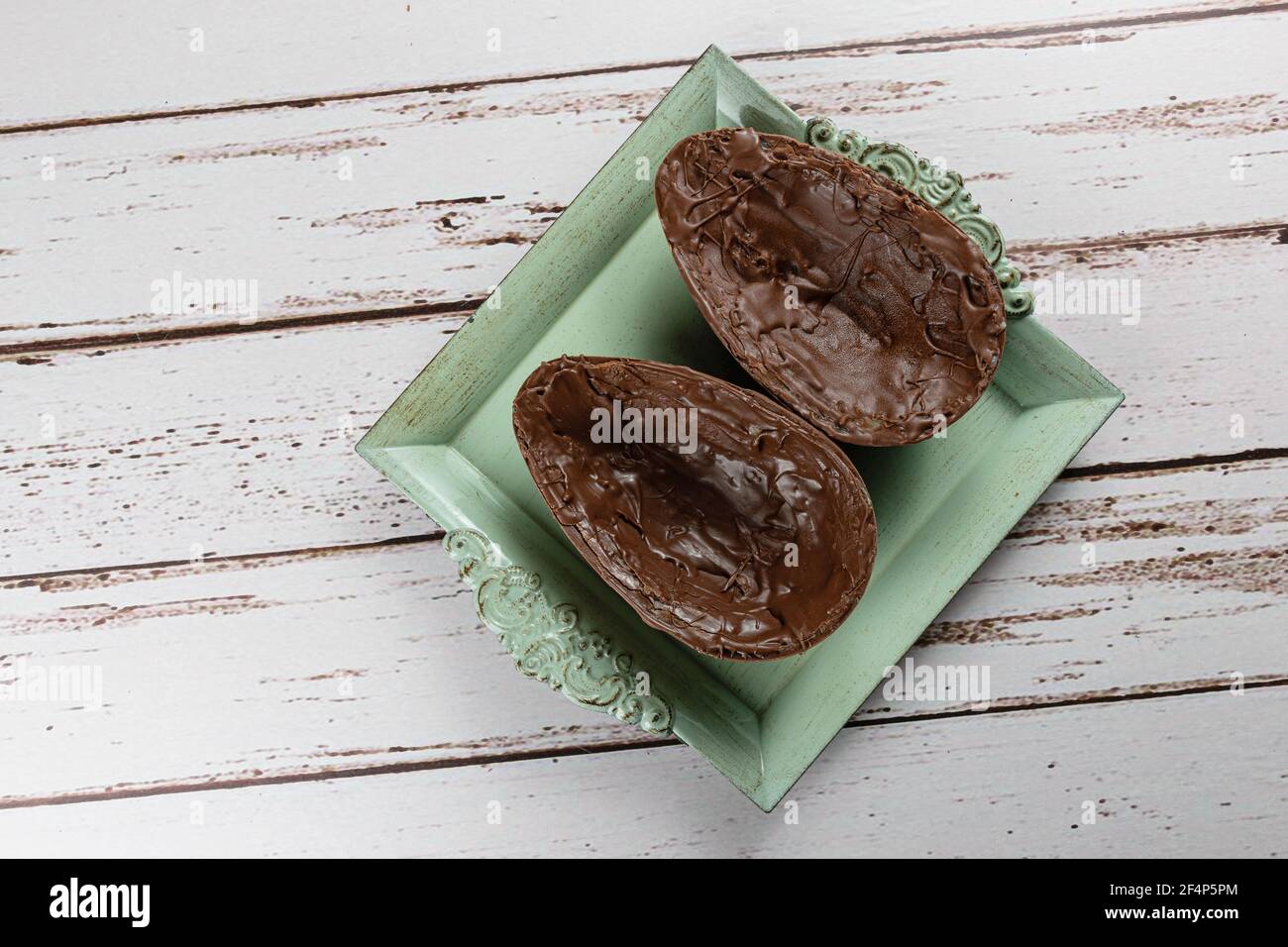 Dos mitades de huevo de Pascua de chocolate, en una bandeja vieja pequeña (con espacio de copia). Foto de stock