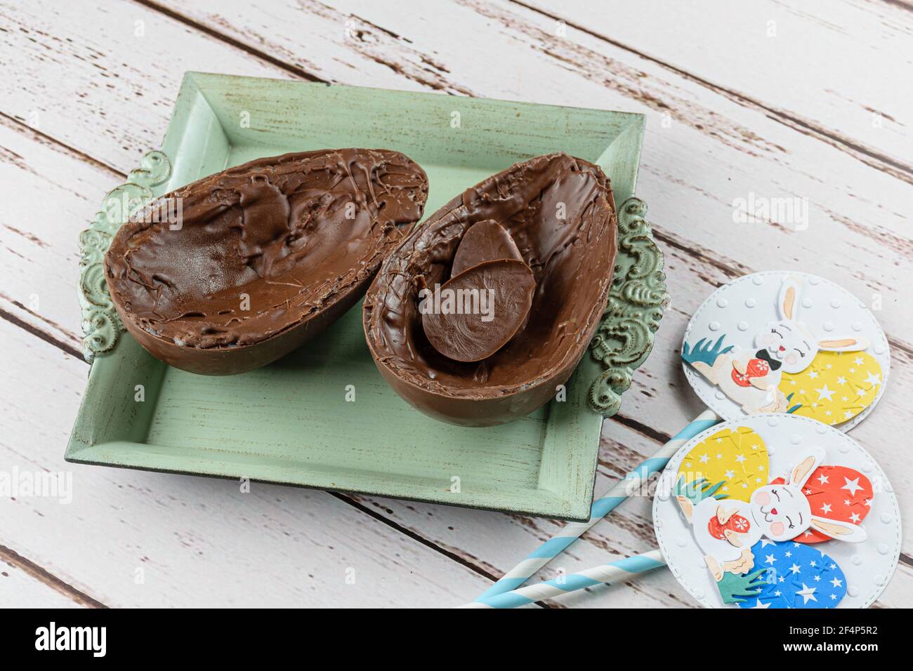 Dos mitades de huevo de Pascua de chocolate, en una pequeña bandeja vieja rellena con pequeños choclolates. Foto de stock