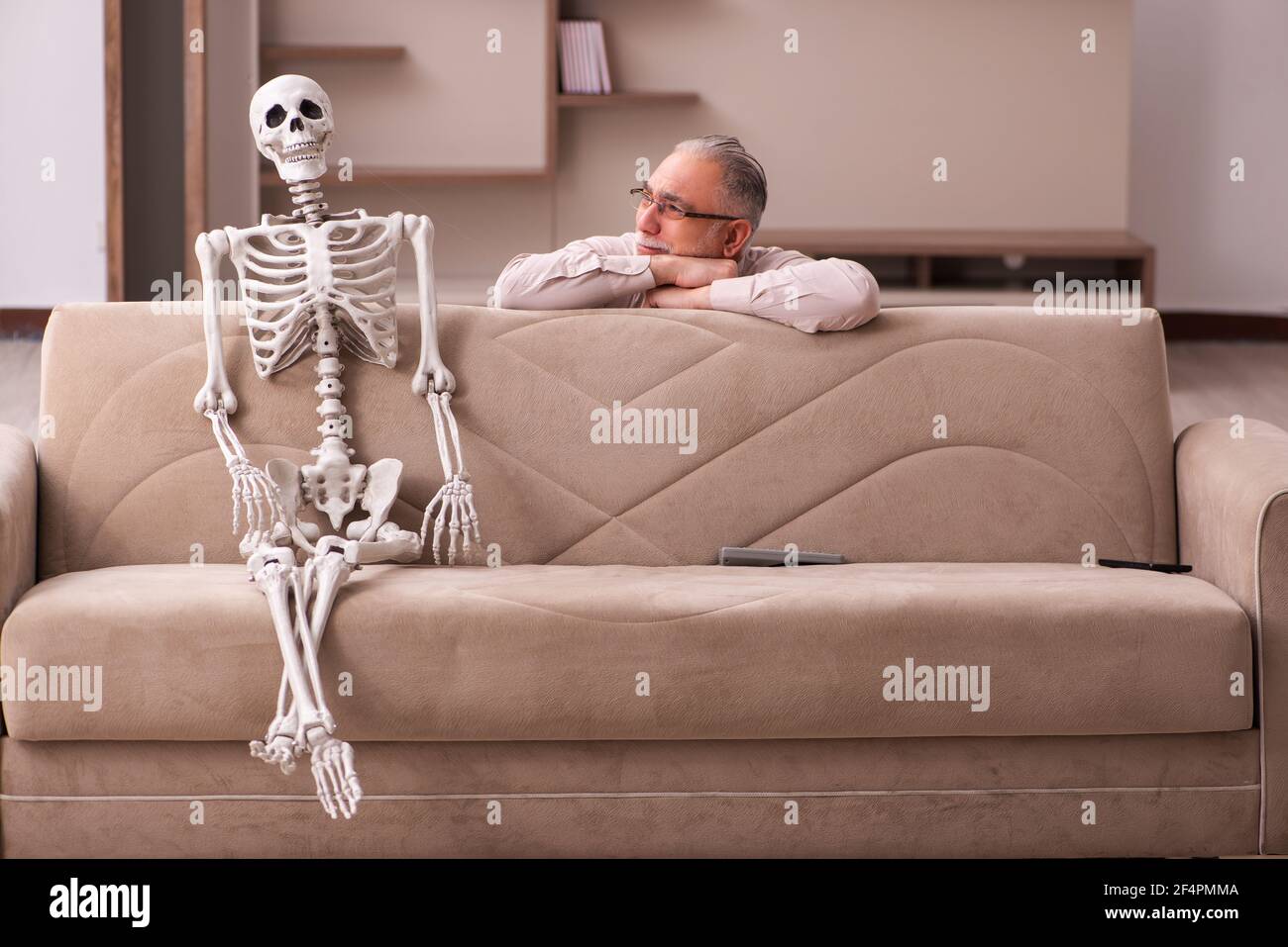 Viejo sentado en el sofá con el esqueleto femenino en el concepto de amor  eterno Fotografía de stock - Alamy