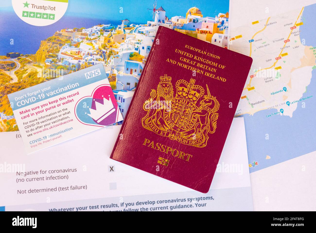 Concepto de pasaporte de viaje de la vacuna COVID 19 del Reino Unido, con tarjeta de registro de vacunación NHS, pasaporte de la UE del Reino Unido, resultado negativo de la prueba, folleto de vacaciones y mapa de España Foto de stock