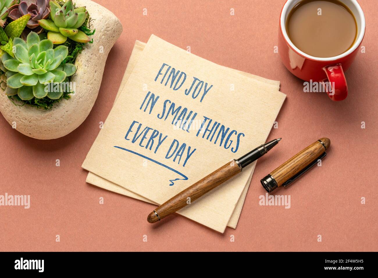 encuentre alegría en pequeñas cosas cada día - escritura inspiradora en una servilleta con una taza de café, positividad, mentalidad y concepto de desarrollo personal Foto de stock