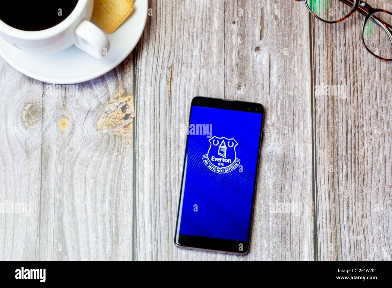 Un teléfono móvil o celular colocado sobre una madera Mesa con la aplicación Everton Football Club abierta en la pantalla Foto de stock