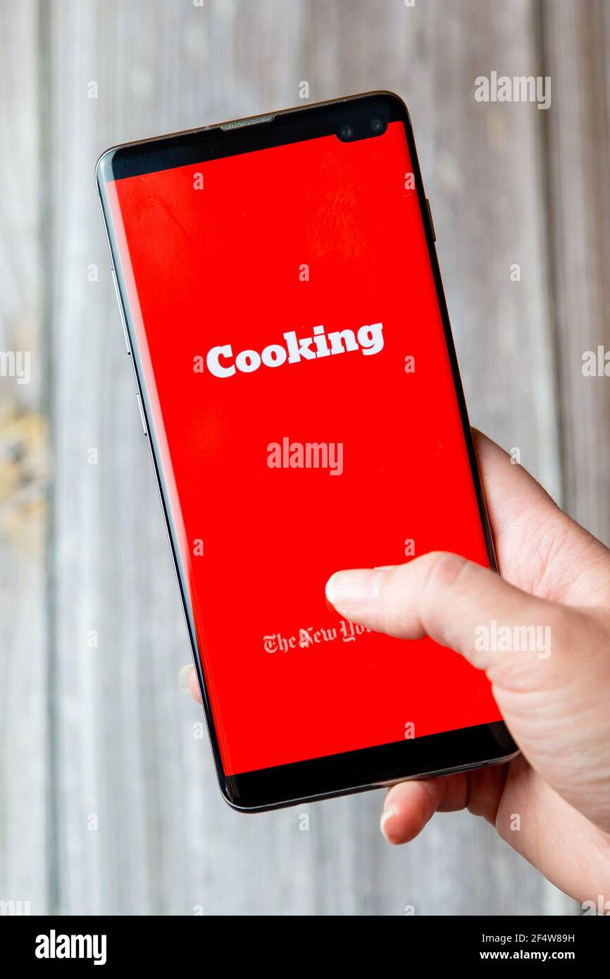 Un teléfono móvil o celular que se mantiene en un Mano con la aplicación de cocina New York Times abierta pantalla Foto de stock