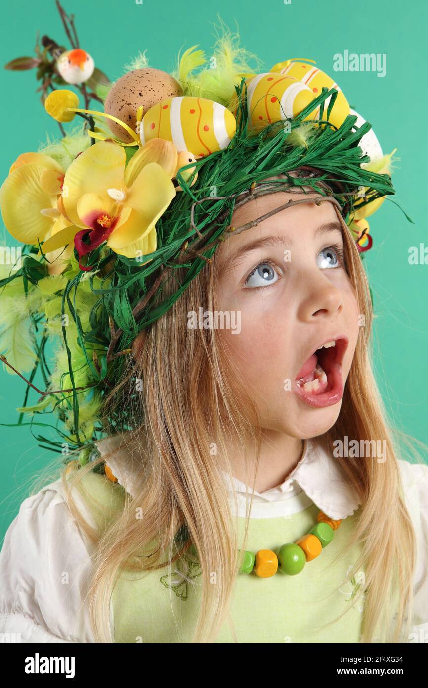 Linda niña vestida con un sombrero de paja con huevos de Pascua amarillos,  flores de primavera, plumas y pájaros. El niño mira hacia arriba abriendo  la boca Fotografía de stock - Alamy