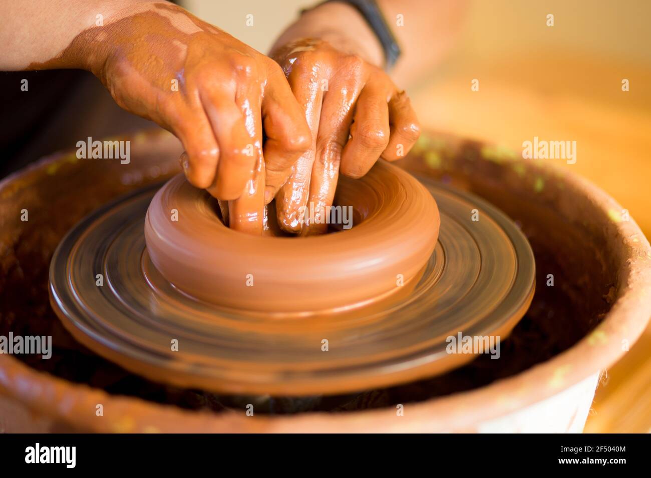 Hands of potte hace platos de cerámica en la rueda de potter. Escultor en el taller hace el producto de arcilla closeup Foto de stock